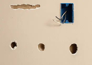 Multiple holes and damage from electrical work in Bothell home wall