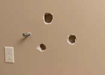 Multiple large holes from failed TV mounting attempts in Bothell living room wall