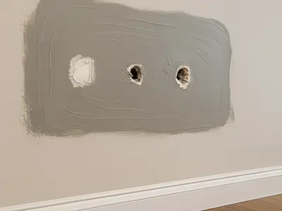 Large holes from failed TV mounting being professionally repaired in Bothell living room